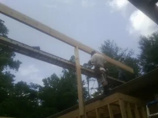 Carpenter setting a ridge beam over a new addition frame — Ice Dam Removal by Roofing Brothers in Allred