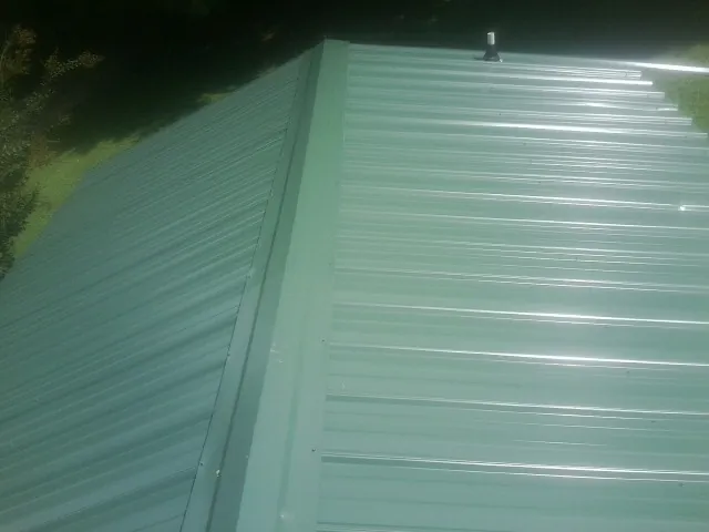 New green metal panels meeting at the ridge of a roof — Flat Roof Repair work by our crew in Allred