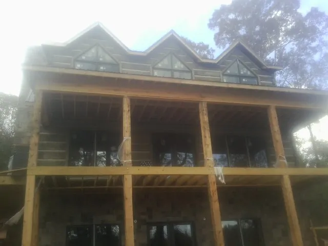 Dormers and porch framing on a large log home under construction — Roof Coating work by our crew in Allred
