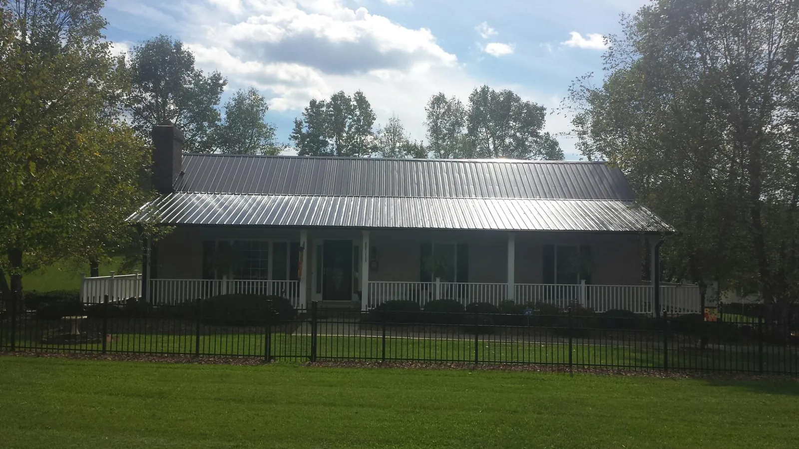 Gray metal roof on a brick ranch with a full width front porch — Gutter Guard Installation work by our crew in Allred