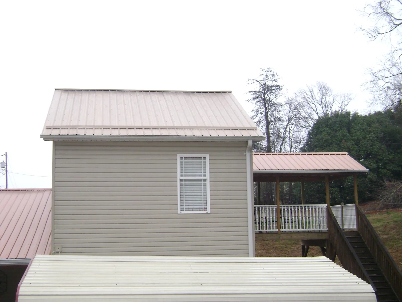Tan metal roofs on a two story addition and attached porch, from a Roof Replacement job in Allred