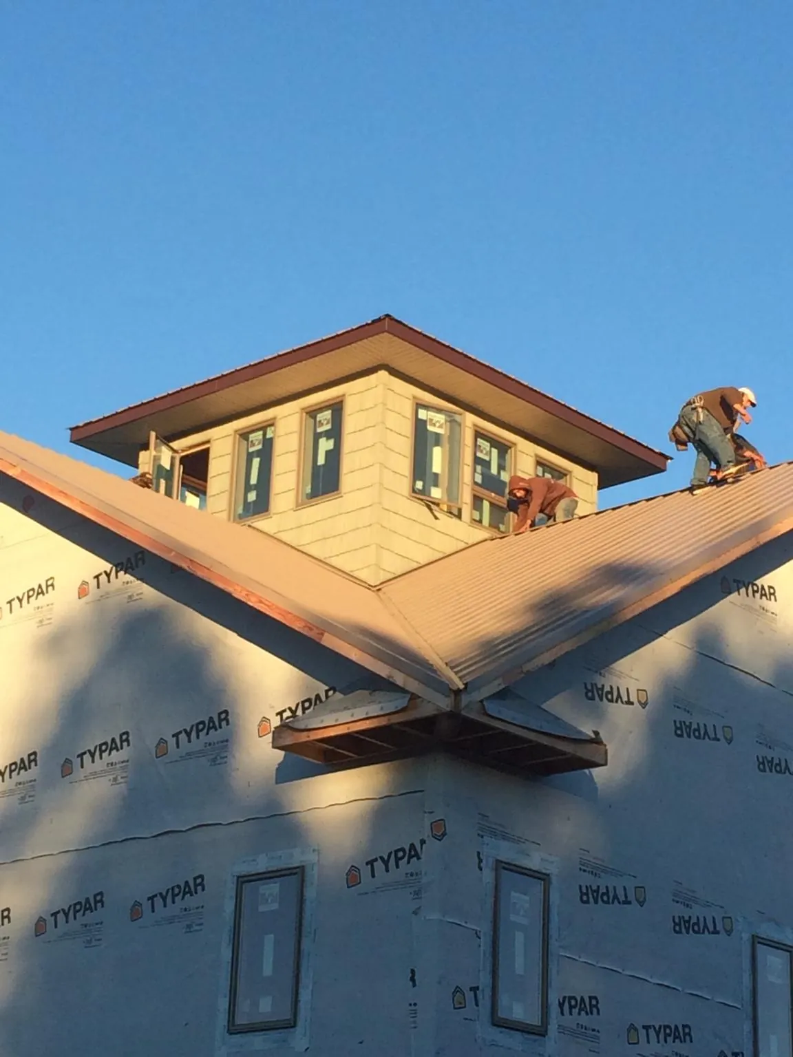 Roofers working around a rooftop cupola on a new metal roof at sunset — Roof Waterproofing in Allred by Roofing Brothers
